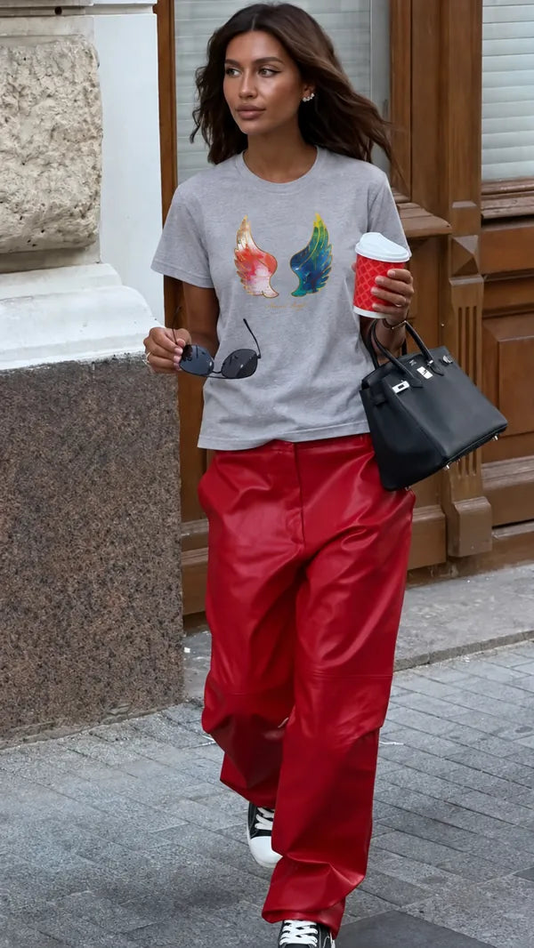 Grey wing-print T-shirt paired with red trousers on a city walk