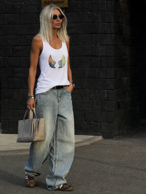 White wing-print tank top styled with wide light denim on a city street