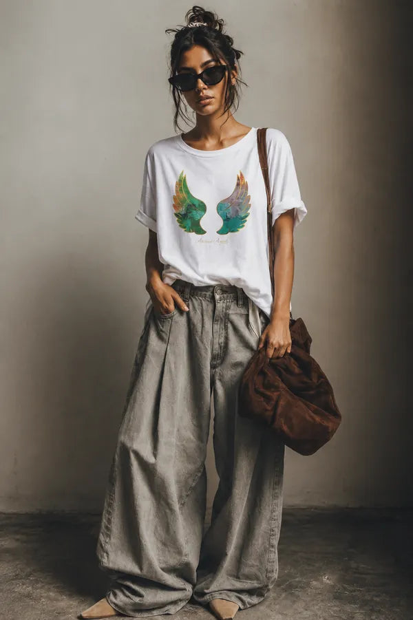 White wing-print T-shirt styled with wide grey trousers and a suede bag